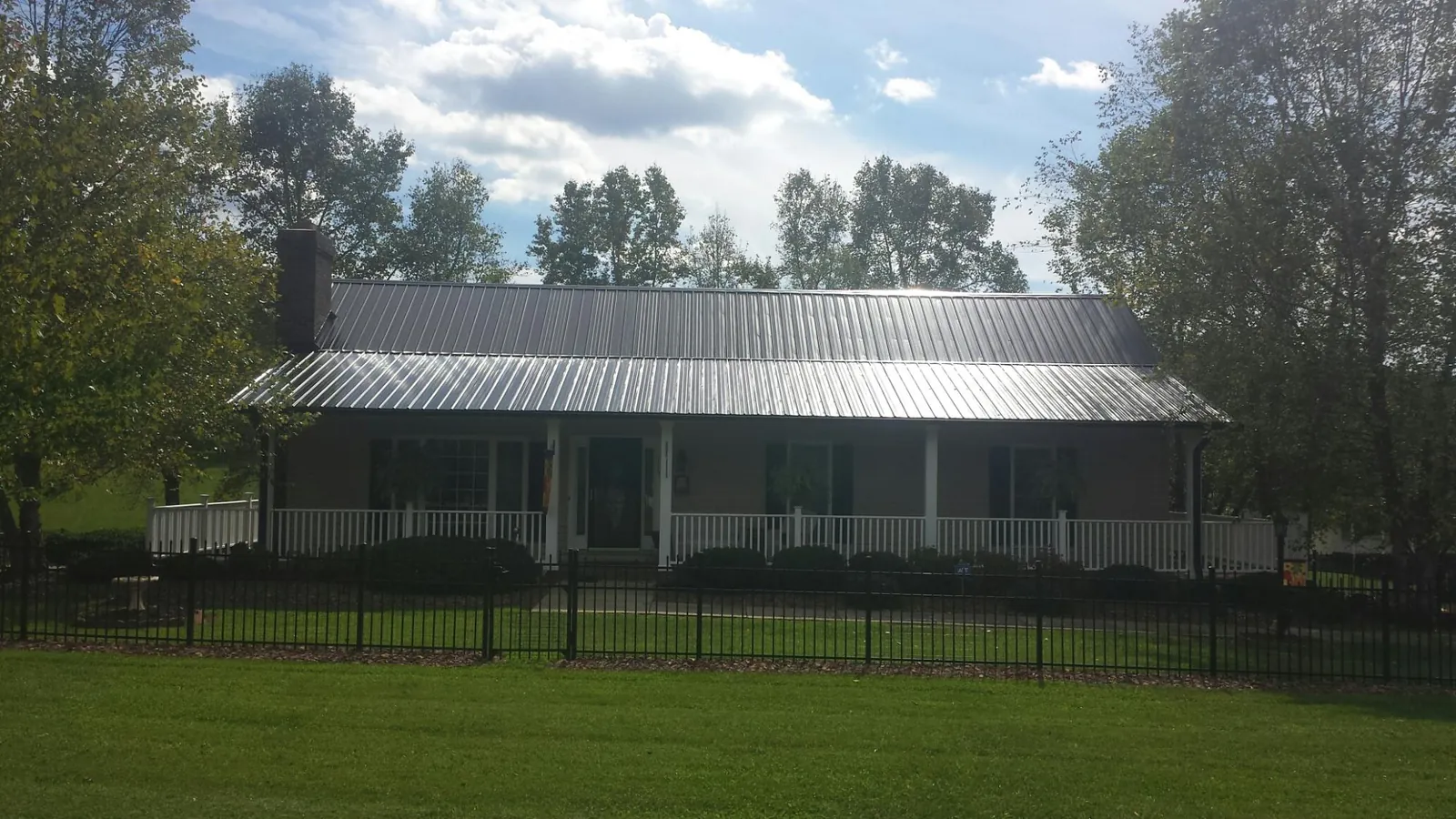 Gray metal roof on a brick ranch with a full width front porch — Gutter Guard Installation work by our crew in Whittier