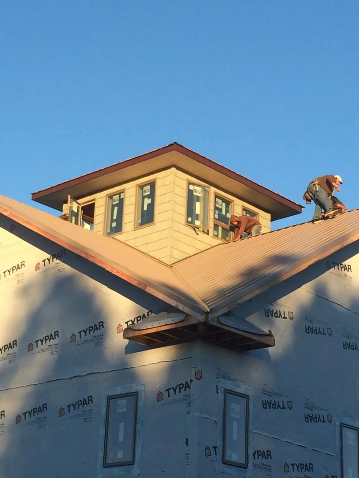 Roofers working around a rooftop cupola on a new metal roof at sunset — Roof Waterproofing in Whittier by Roofing Brothers